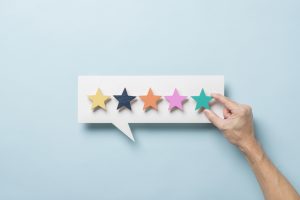 Five coloured stars on a speech bubble shaped board with a hand