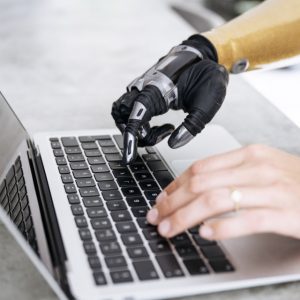 robotic hand and human hand on a keyboard