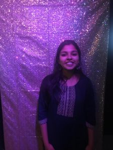 Woman standing in front of a sparkly purple curtain