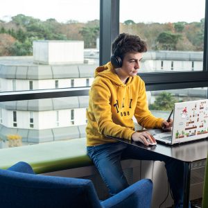 Male in yellow jumper working on a laptop