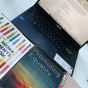 Two text books laid beside a laptop