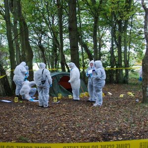 Students in hazmat suits in a forest at a practice crime scene