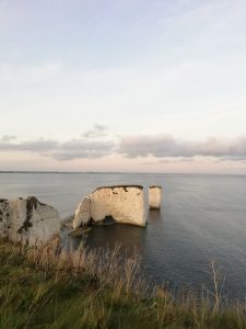 Old harry rocks stands with a calm sea around it and a blue sky behind