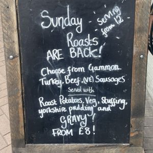 A blackboard with writing on saying Sunday roasts are back