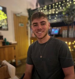 Jack is smiling at the camera with fairy lights behind him