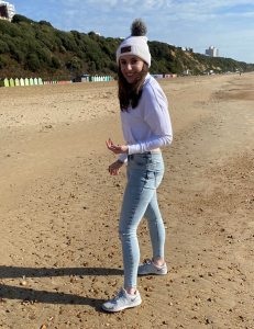 Mollie standing on the beach wearing a beanie hat