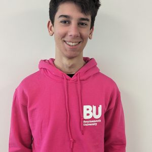 Male student facing to camera wearing a pink hooded jumper