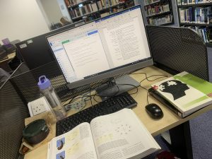 Desk set up with a computer and textbooks and a water bottle