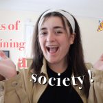 Kiah smiles to the camera with her arms raised lifting up the words on the screen 5 perks of joining a society!