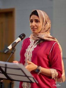 A woman delivering a poem speaking into a microphone