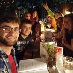 Eduard and a group of friends at a restaurant take a group photo at the table