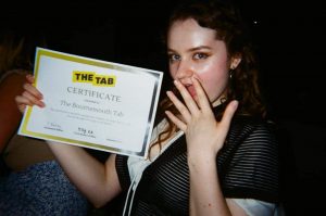 Girl smiling, holding award certificate saying "The Bournemouth Tab"