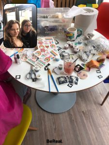 Two smiling women standing by a table with fake tattoos and paintbrushes, in the Bournemouth University SUBU building 