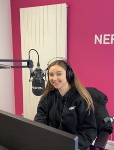 Hannah sat in the Nerve Radio studio with head phones on in front of the microphone.