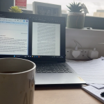 Photo showing someone studying with work on a laptop screen and a cup of tea.