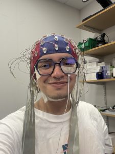 Juan, an MSc Psychology student, wearing a head cap with connected cables during a neuroscience research experiment.